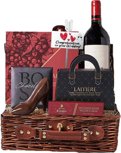 A wicker basket containing a bottle of red wine, chocolate items including a shoe-shaped piece, and a card with "Congratulations on your Wedding!" text and heart illustrations.