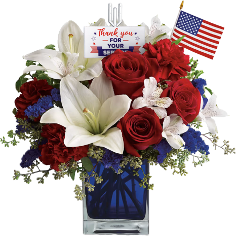 A patriotic flower arrangement with red roses, white lilies, and blue flowers in a blue vase. An American flag and a "Thank you for your service" card are inserted among the blooms.