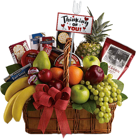 A wicker basket filled with a variety of fruits including bananas, oranges, apples, a pineapple, and grapes. It also contains tea, cookies, chocolates, and cheeses. A sign reads "Thinking of You" with a red bow on the basket.