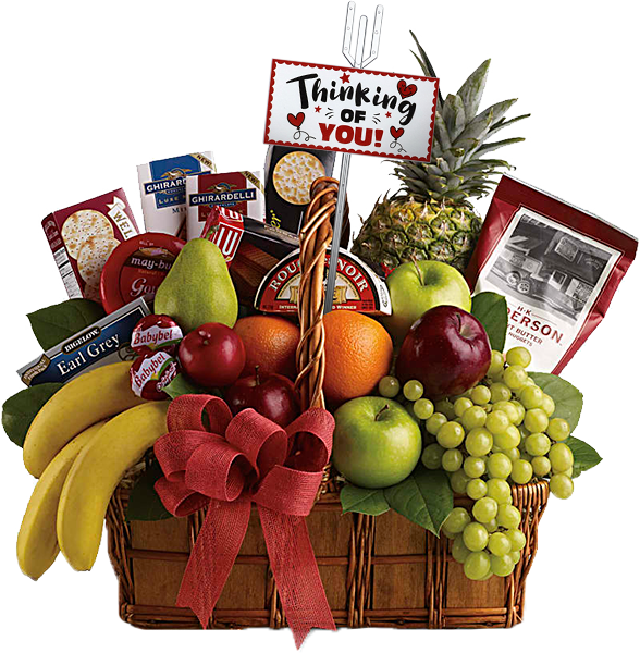 A wicker basket filled with a variety of fruits including bananas, oranges, apples, a pineapple, and grapes. It also contains tea, cookies, chocolates, and cheeses. A sign reads "Thinking of You" with a red bow on the basket.