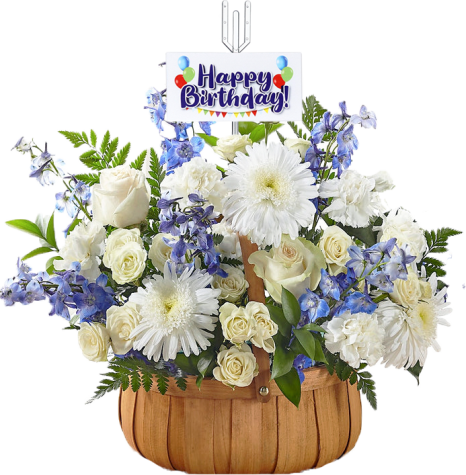 A wooden basket filled with white roses, gerbera daisies, and blue delphiniums, topped with a "Happy Birthday" card featuring colorful balloons and bunting.